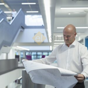 Инженер изучает проектные чертежи для систем.