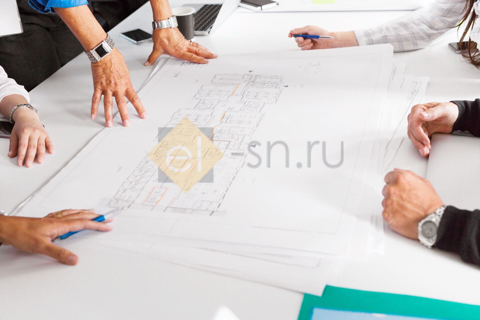 Команда архитекторов обсуждает проект с чертежами